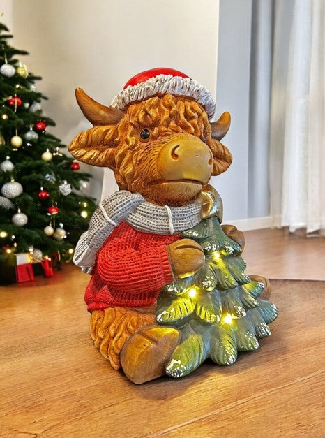 LED Deko Hochlandrind mit 4 LED sitzend mit Tannenbaum in der Hand