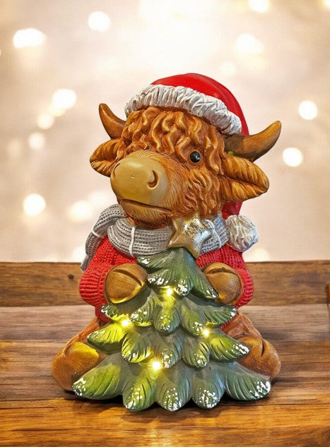 LED Deko Hochlandrind mit 4 LED sitzend mit Tannenbaum in der Hand