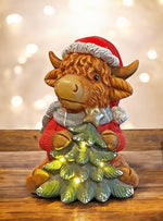 LED Deko Hochlandrind mit 4 LED sitzend mit Tannenbaum in der Hand