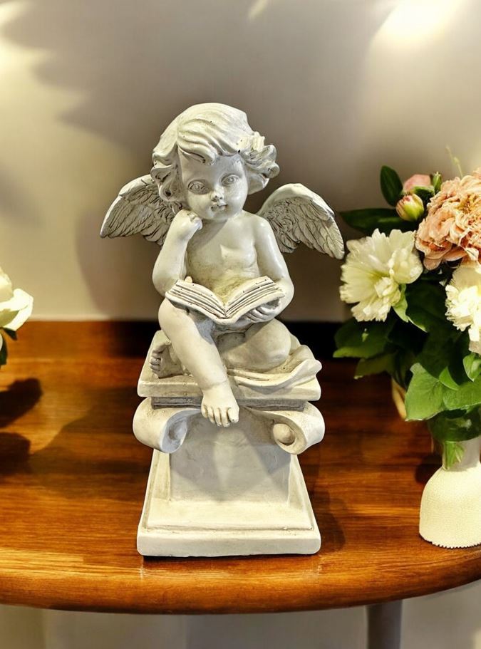 Engelfigur sitzend auf Stein mit Buch in Grau